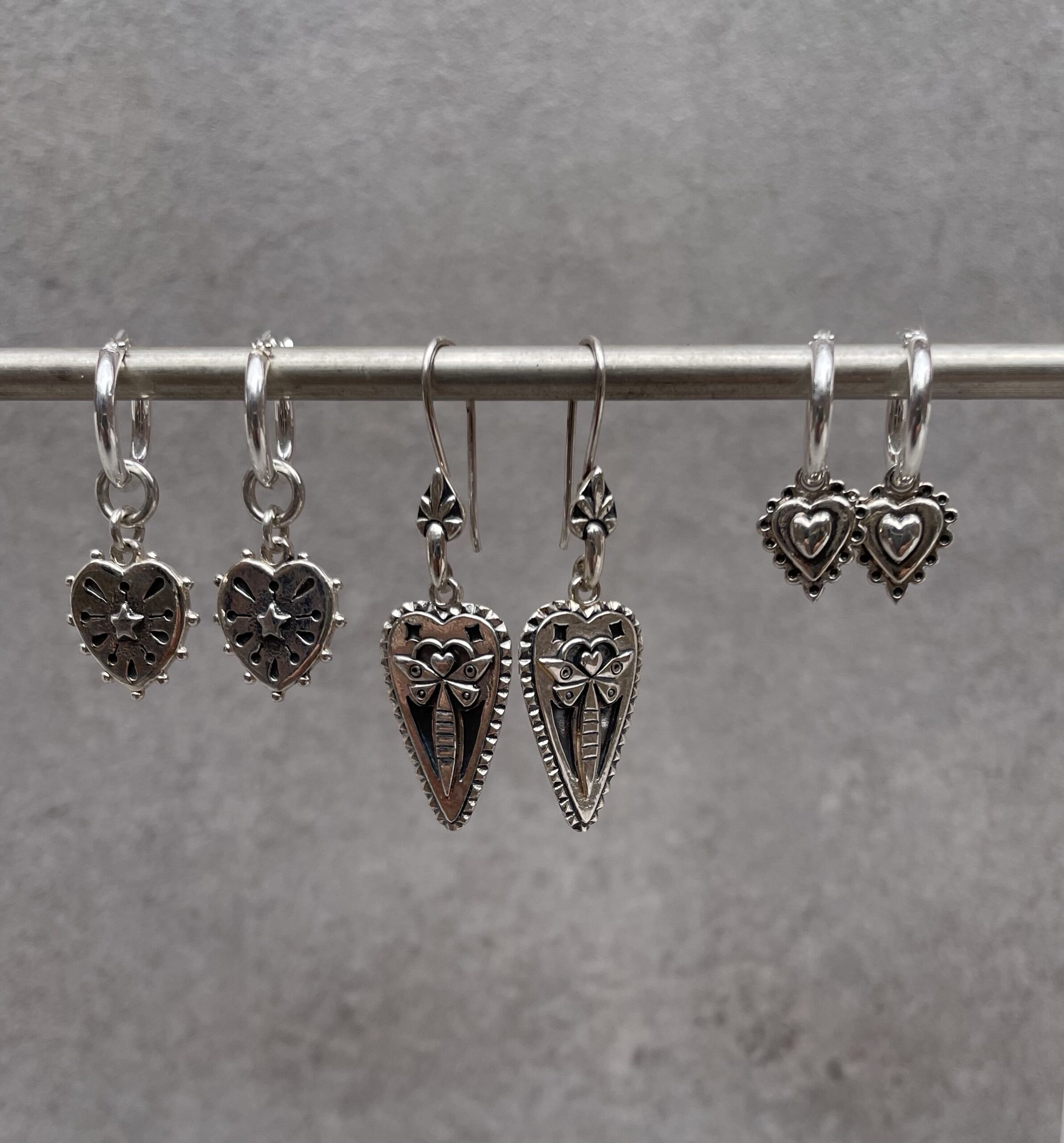 3 heart earrings on bar for size comparison